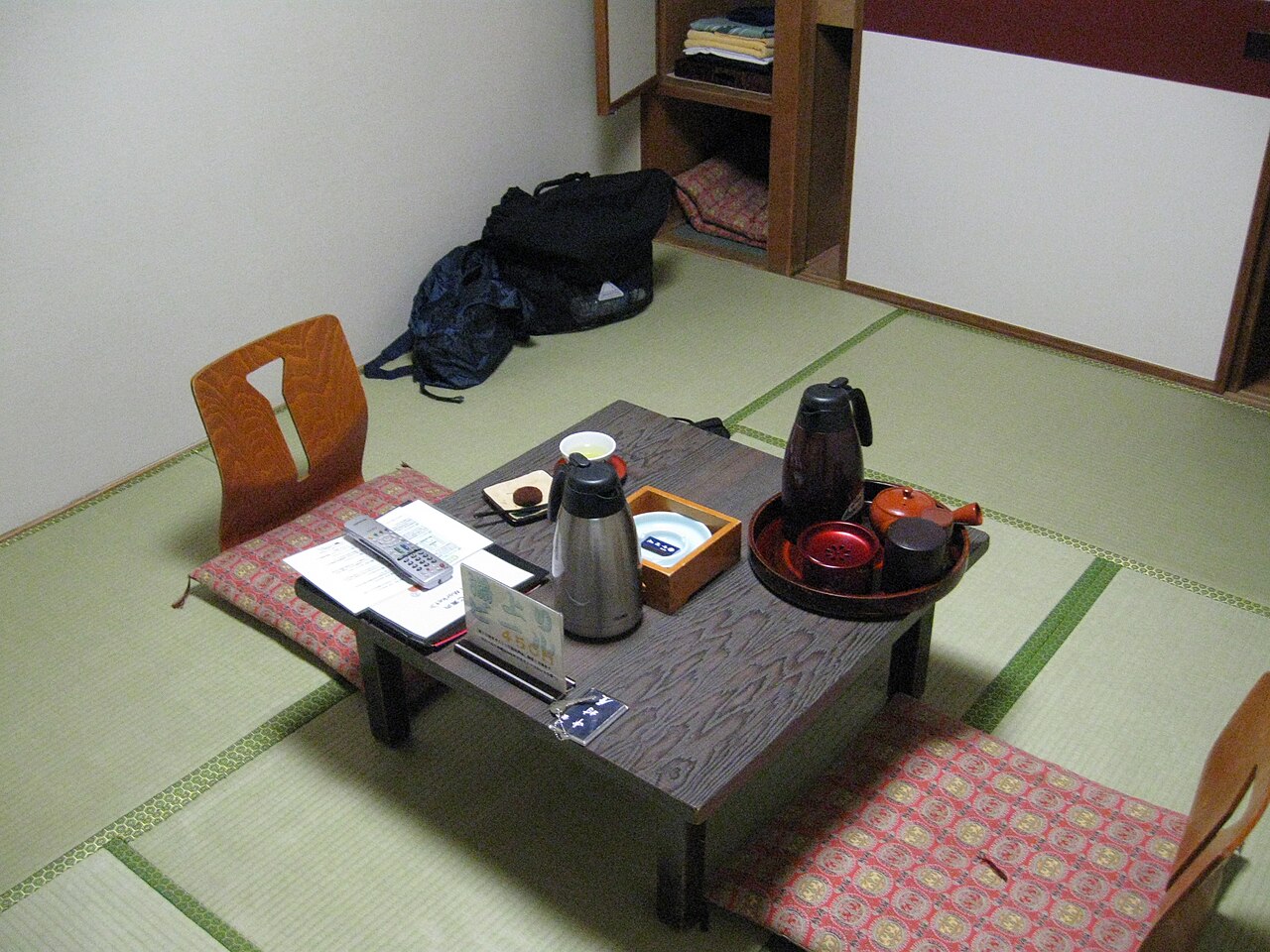 日式旅馆的榻榻米房间，矮桌上摆着茶具，桌旁有坐垫。